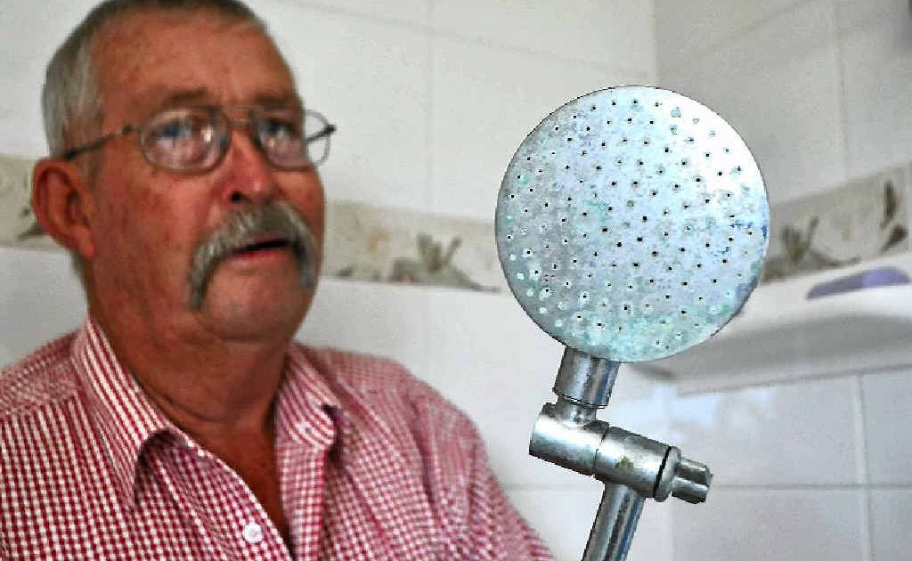 Pratten resident Robert Holt compares a shower head used when the home was connected to the town’s water supply with the new one installed since they put down their own bore.